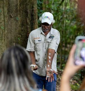 a person taking a picture of a man standing next to a tree