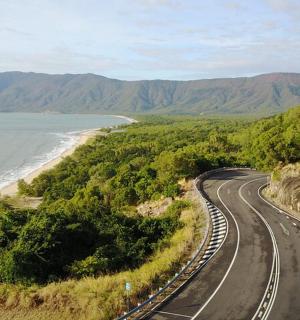 an empty road next to a beach and the ocean