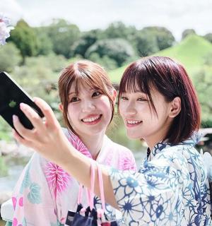 两个女人并排站着，手里拿着手机