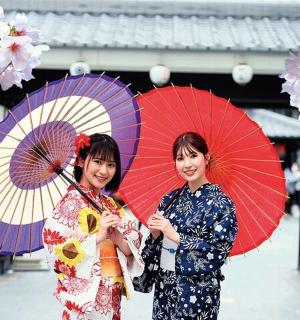 two women in kimonos are holding umbrellas