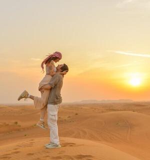 一名男子背着一名女子穿越沙漠