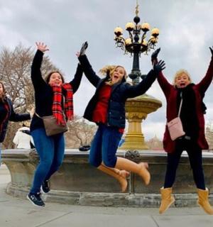 skupina žen skákajících před fontánou
