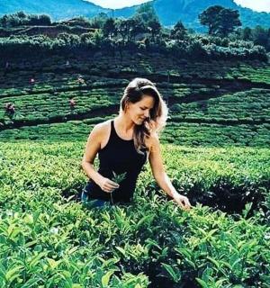 a woman sitting in a field talking on a cell phone