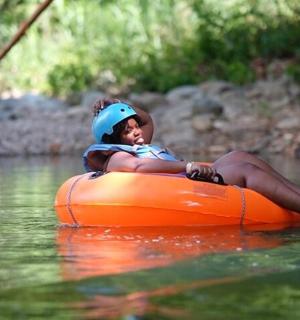 a young girl sitting on an orange raft in the water