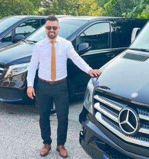 一名打着领带的男子站在一辆车旁边