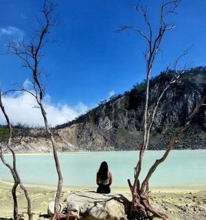 一位女士坐在靠近水域的海滩上