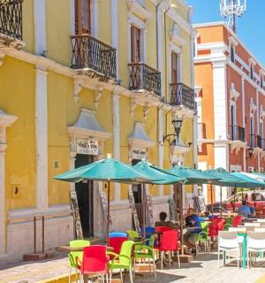 a group of tables and chairs with umbrellas on a street