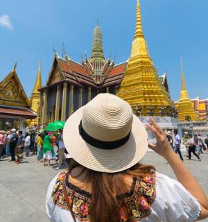 一位戴着帽子的女子正在拍摄一座寺庙