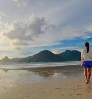 a woman standing on a beach looking at the ocean