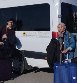 two people standing in front of a bus with their luggage