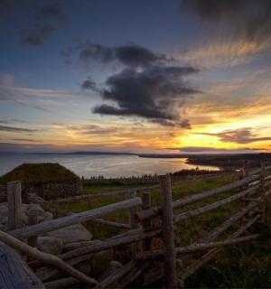 a sunset over the ocean with a wooden fence