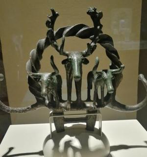 a metal sculpture of a deer with horns on a table