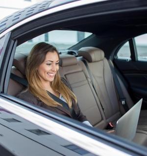 жена седи на задњем седишту аутомобила са лаптопом