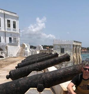 一名男子站在一堆大炮旁边