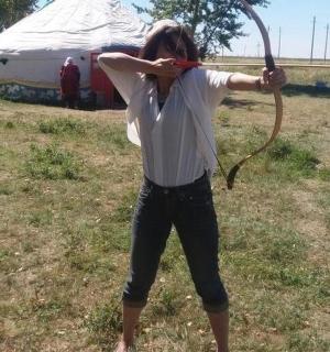 a woman holding a bow and arrow in a field