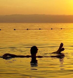 žena ležící ve vodě při západu slunce