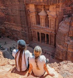 dva lidé sedící na skále a dívající se na starobylou budovu