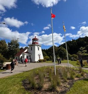 一座红色屋顶的白色灯塔,周围有人走动