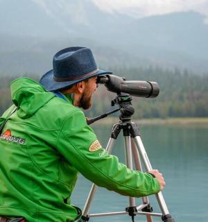 一名身穿绿色夹克的男子用相机看着水