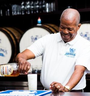 a man standing in front of a table with a bottle of wine