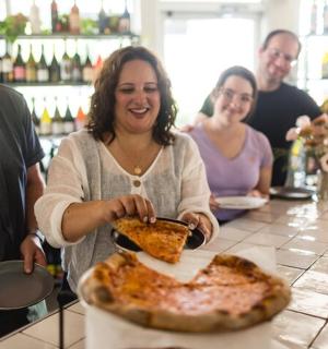 a woman standing at a counter with a pizza