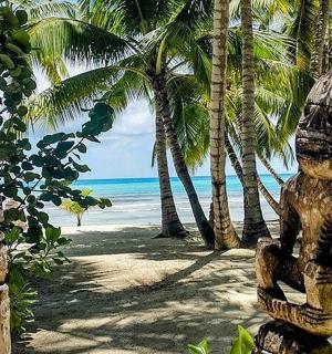 a couple of statues on a beach with palm trees