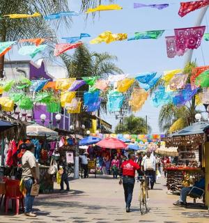 un carrer amb gent caminant per un mercat amb paraigües