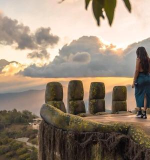 a woman standing on top of a hill looking at the sunset
