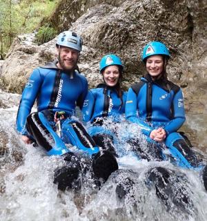 tři lidé sedící na skále u vodopádu
