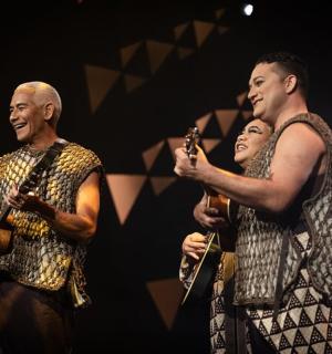 dva muži a žena hrající na hudební nástroje na pódiu