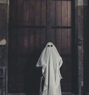 a person in a ghost costume standing in front of a door