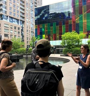 a group of people standing around a fountain in a city