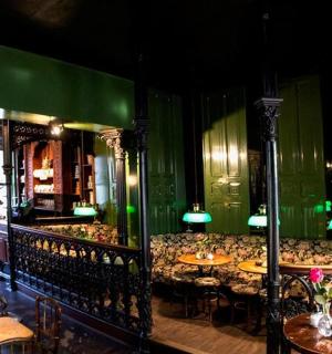 restaurace se stoly a židlemi a zelenými stěnami