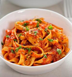 bílá miska těstovin s omáčkou a zelenou cibulkou