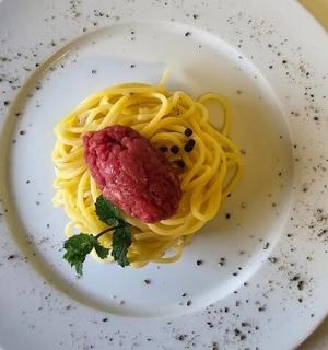 a plate of pasta with a piece of meat on it