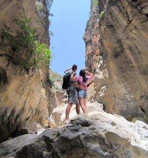 two people standing on some rocks in a canyon