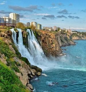 a waterfall on a cliff next to a body of water