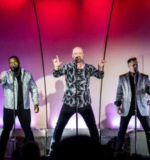 skupina tří mužů stojících na pódiu