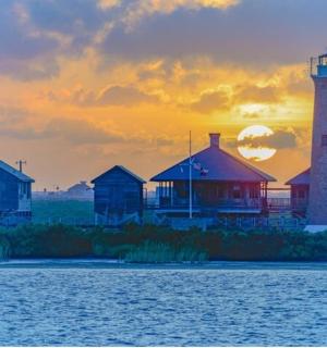 Skupina domů a maják při západu slunce