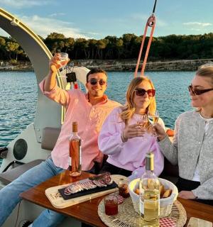 三个人坐在船上，手里拿着酒杯