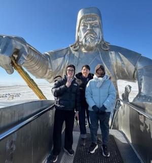 three people standing in front of a statue