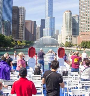 Skupina lidí sedících na bílých židlích před městem