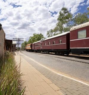 一列红色火车停在建筑物旁边的轨道上