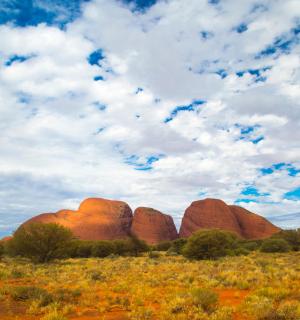 a group of red rock formations in a field