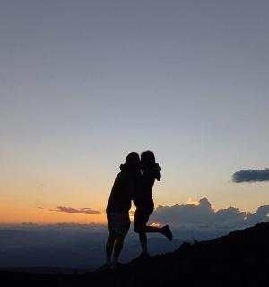 Pár líbající se na vrcholu hory při západu slunce