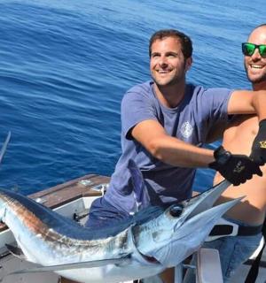 两个男人在船上拿着一条鱼