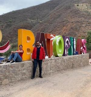 a man and a woman sitting on a wall with a sign