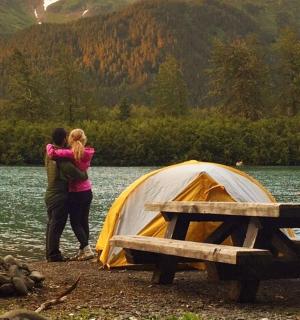 两个人站在湖边的帐篷旁边