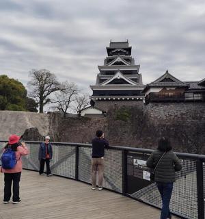 一群人站在桥上看着一座城堡