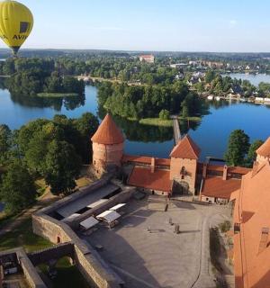 a hot air balloon flying over a castle on a lake